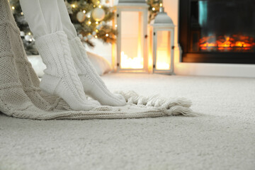 Obraz na płótnie Canvas Woman in knitted socks resting near fireplace at home, closeup