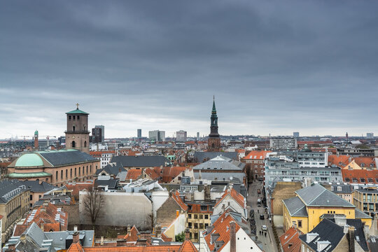 Aerial view of old downtown of Copenhagen City from the Round Tower (Rundetaarn) in rainy misty day with cloudy sky with red house roofs and Church of Our Lady (Vor Frue Kirke) and St. Peter's Church