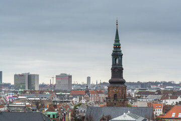 Fototapeta premium Aerial view of Copenhagen City from the The Round Tower (Rundetaarn) in rainy misty day with cloudy sky and building of St. Peter's Church bell tower