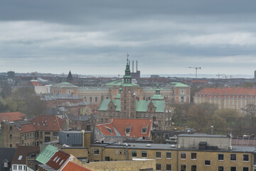 Fototapeta premium Aerial view of old downtown of Copenhagen City from the The Round Tower (Rundetaarn) in rainy misty day with cloudy sky with red house roofs and churches