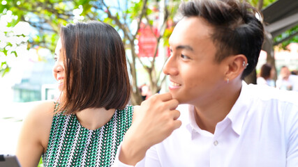 Young asian couple relaxing outdoor at a restaurant table