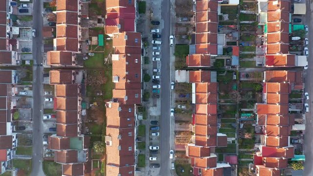 Rows of terrace houses in a mill town. Townhouses with red roofs in a company village or monotown in Europe. Housing project in suburban neighborhood. Aerial drone top down view.