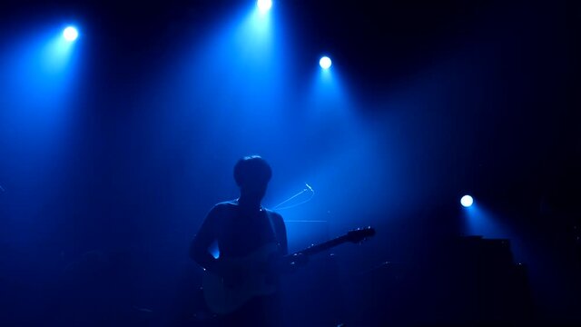 Asian male musicians playing guitar on concert event stage