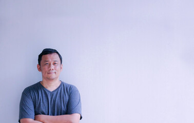 portrait of a middle Aged Man Standing with arms folded on Grey Background with Copy Space