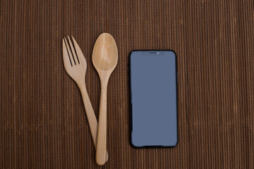 Spoon and fork on table with smart phone.