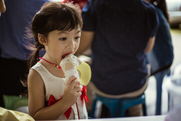 Portrait of Cute Asian girl eating icecream outdoor. Life during covid-19 pandemic.