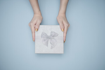 Fototapeta na wymiar Female's hands holding gift box with blue background.