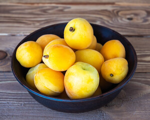 Ripe apricots in a deep cup on a wooden background