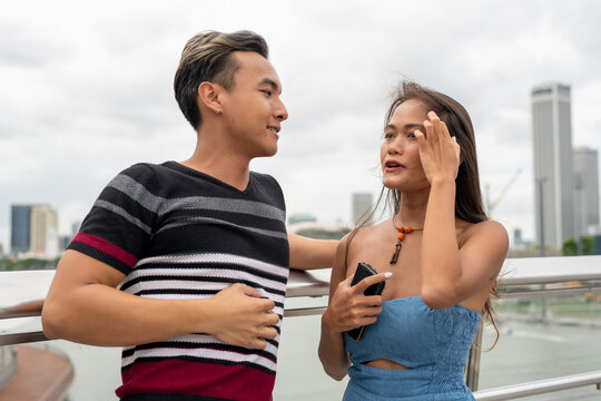 Asian young couple talking standing on a city bridge outdoor