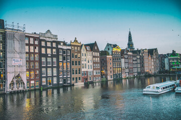 Obraz premium AMSTERDAM, THE NETHERLANDS - APRIL 25, 2015: Traditional houses and buildings on the canal with boats on the water