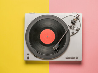 Top view of a vinyl record player on a red and yellow background.