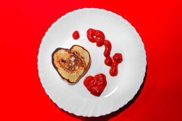 pancakes and ketchup in the shape of a heart on February 14. food for Valentine's day on a red background.