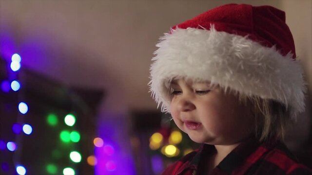 a child in red clothes is sitting waiting for the new year. the concept of celebrating Christmas at midnight. holiday costume