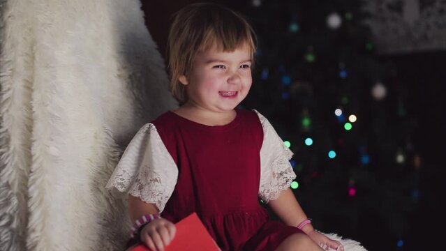 a child in red clothes is sitting waiting for the new year. the concept of celebrating Christmas at midnight. holiday costume. a girl writes a letter to Santa Claus. wish list
