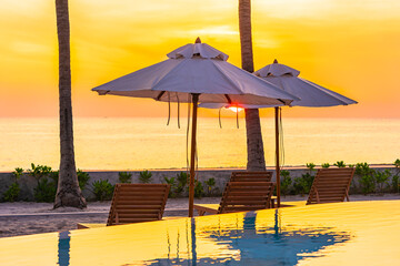Umbrella and deck chair around outdoor swimming pool in hotel resort