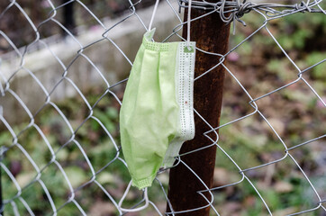 Forgotten surgical mask on a fence