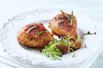 Baked chicken drumsticks with fresh herbs on bright background. Close up.	