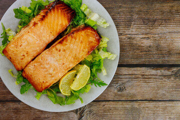 Grilled salmon fillet with green salad on gray plate.