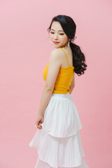 Full length portrait of a young woman, shot on pink background. she looks over her shoulder