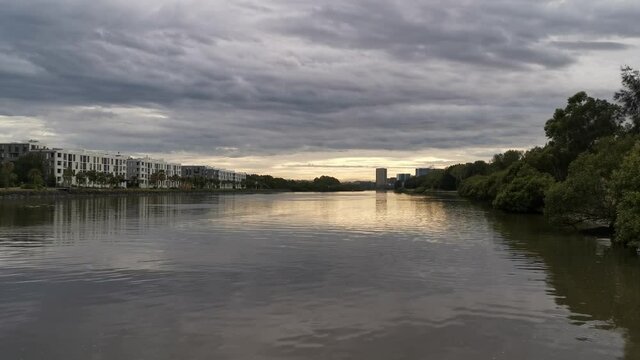 Calm river with reflections of morning cloudy, trees and apartments
 on water, Parramatta river, Wilson Park, Sydney, New South Wales, Australia
