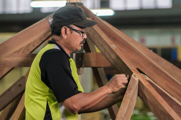 Carpenter using bolt and nut in installation of roof rafters on a new gazebo construction project .