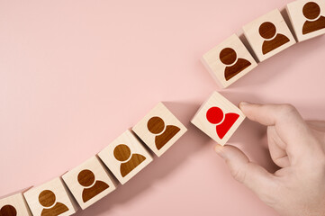 Hand choosing a wooden person block from a set. Employment choice concept. Human Resources Hr...