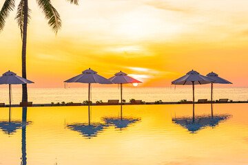 Umbrella and deck chair around outdoor swimming pool in hotel resort
