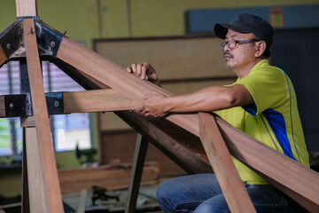 Carpenter using bolt and nut in installation of roof rafters on a new gazebo construction project .