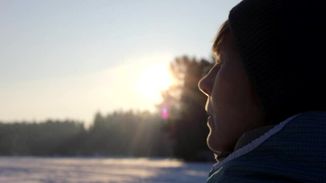 Young woman blows steam from her mouth on a sunny winter day