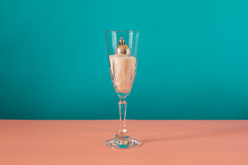 Gray ornament inside the glass on pink and blue background. Winter concept