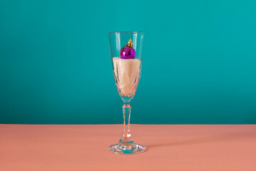 Purple ornament inside the glass on pink and blue background. Winter concept.