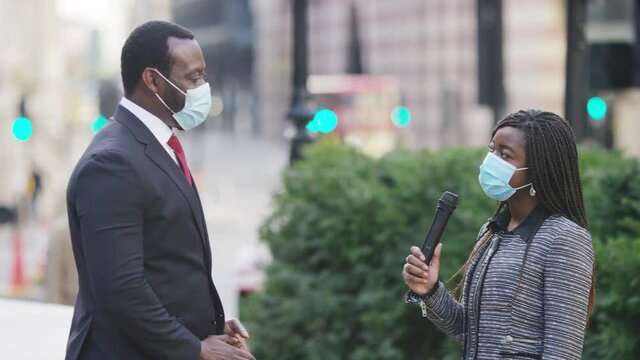 Reporter interviewing an important executive whilst wearing face coverings in the city