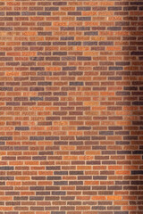 Full frame texture background of a vintage traditional stretcher bond brick wall with varying shades of red, brown and tan, with a lightly textured surface