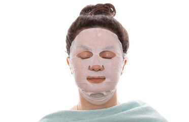 Face care and beauty treatments. Woman with a moisturizing mask on her face isolated on white background. Eyes closed, shoulders covered with towel. Health care, spa concept. Copy space
