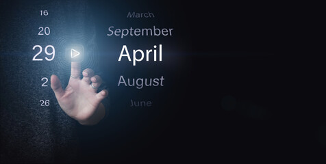 April 29th. Day 29 of month, Calendar date. Hand click luminous icon PLAY and DATE on dark blue...