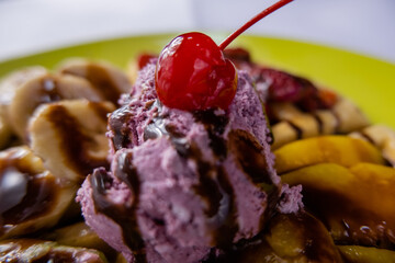 Cherry and ice cream on top of fruit decorated with chocolate syrup