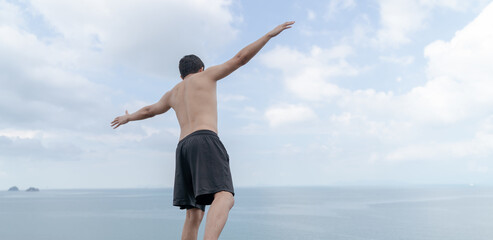Obraz premium Back view of man opened hands with delight at the ocean and sky.