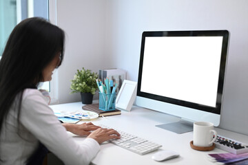 An artist or designer working on computer with white screen at creative workplace.