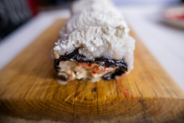 Sushi rolls covered with white cream on cutting board