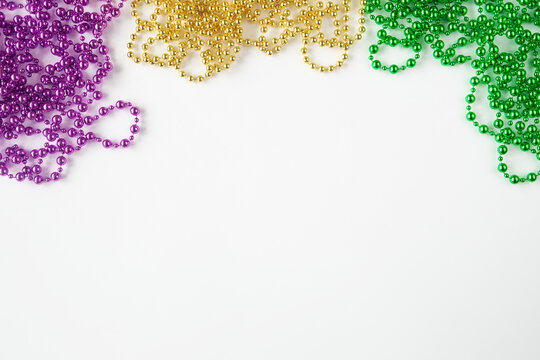 Mardi gras background on white with purple gold green beads and copy space