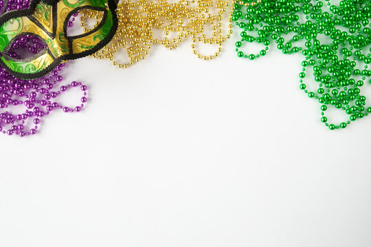 Mardi gras background on white with mask and purple gold green beads and copy space
