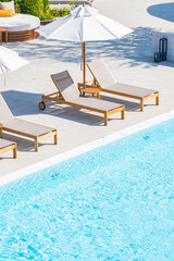 Umbrella and deck chair around outdoor swimming pool in hotel resort - obrazy, fototapety, plakaty
