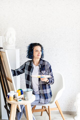 Creative woman with blue dyed hair painting in her studio