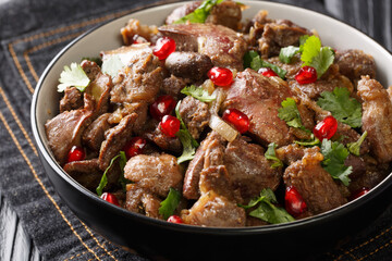 Homemade Kuchmachi made from chicken liver, hearts and gizzards with onions, walnuts and pomegranate close-up in a bowl on the table. horizontal