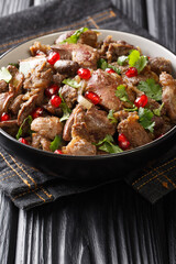 Delicious Kuchmachi made from chicken offal with spices, onions and pomegranate close-up in a bowl on the table. vertical