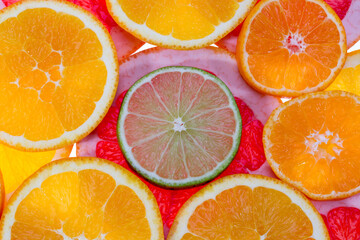 Background of fruit slices of red grapefruit, green lime and mandarin, close up