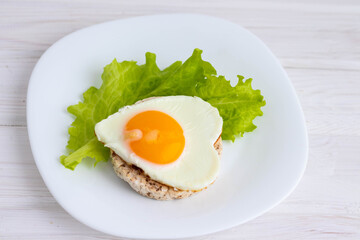breakfast scrambled eggs in the form of a heart on bread and salad.concept of Valentine's day.on a white background
