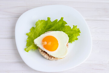 breakfast scrambled eggs in the form of a heart on bread and salad.concept of Valentine's day.on a white background
