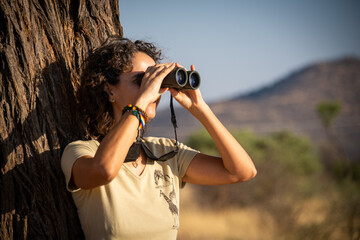 Close-up of brunette by tree using binoculars