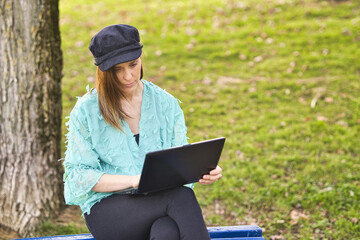 beautiful woman working on a bench in a park at sunset with a laptop. Self-employment concept. business